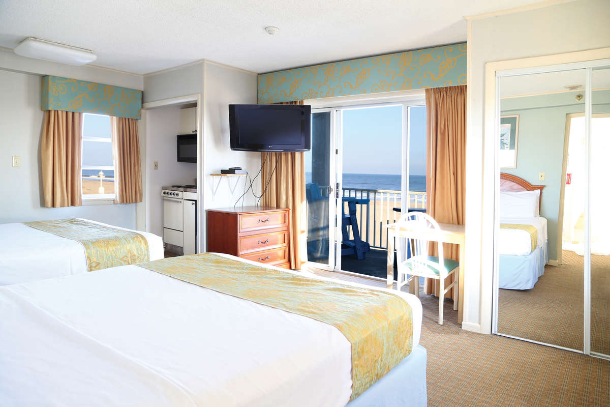 hotel room showing 2 beds a kitchen and an oceanfront balcony